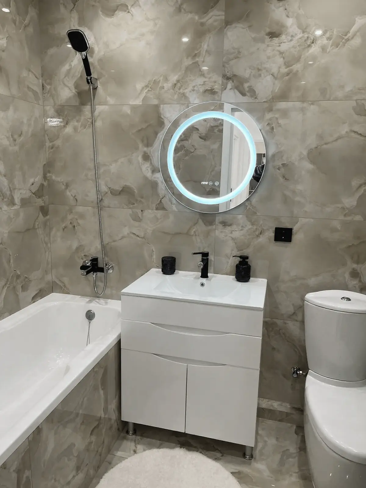 Ванна кімната з плиткою під онікс та круглим дзеркалом